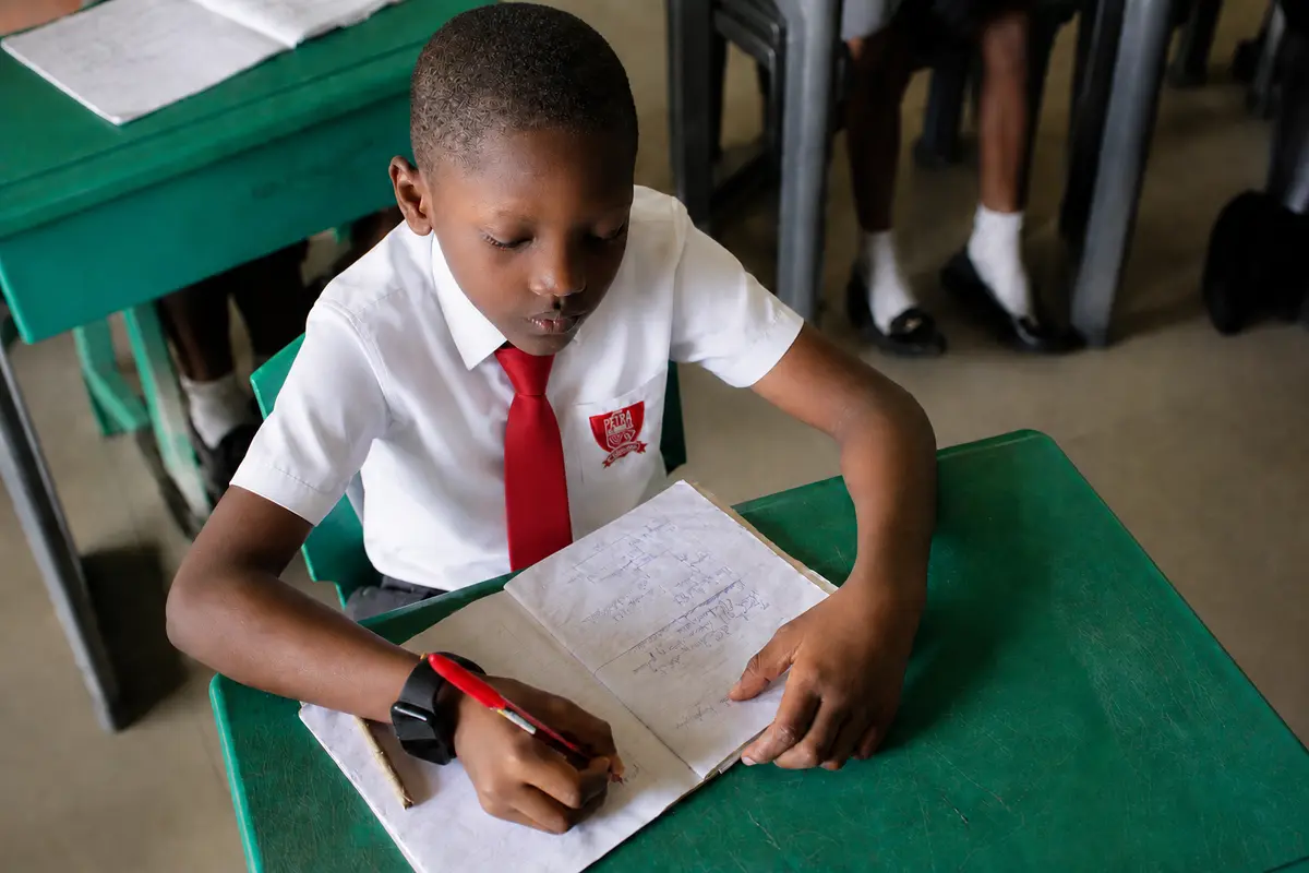 Petra Academy student completing written classwork at his desk