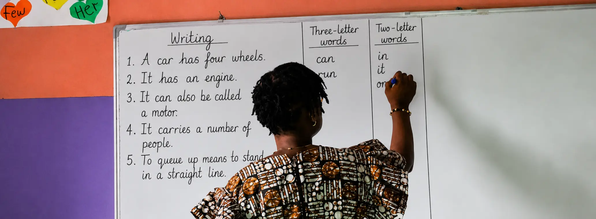 A Petra Academy teacher writing a classroom lesson on the whiteboard