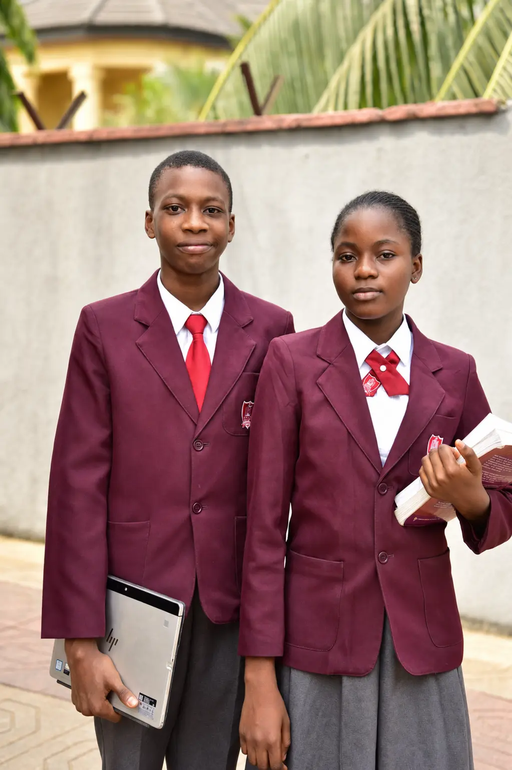 Petra Academy College students holding a laptop and books
